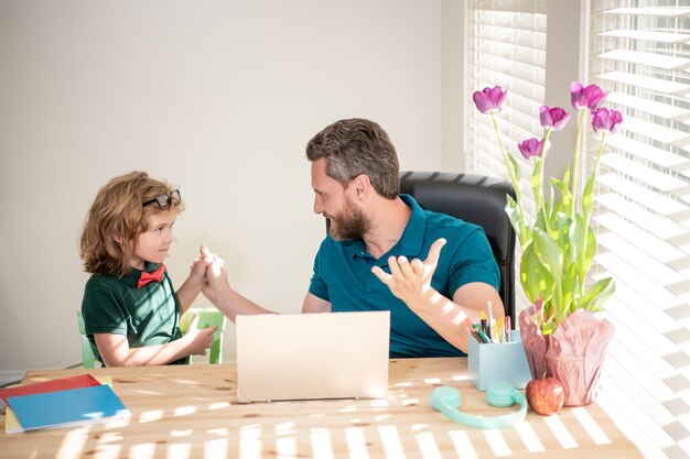 Verrast vader en zoon gebruiken computer thuis familie en ouderschap blog jongen huiswerk maken