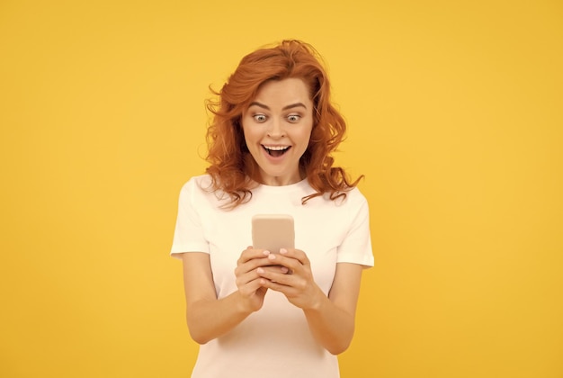 Verrast vrouw chatten in smartphone of online winkelen op gele achtergrond emoties