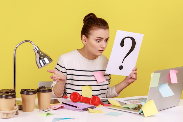 Verrast vrouw kijken naar laptop monitor met papier met vraagteken denkt aan taken