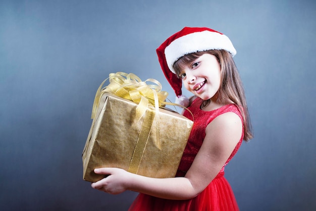 Verrast vrouw met cadeau en kijken op camera over grijze achtergrond