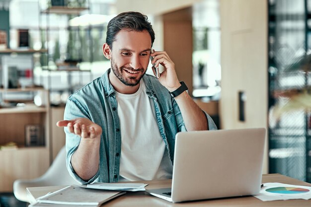 Verrast zakenman kijken naar laptopscherm in café Glimlachende man praten op mobiele telefoon op externe werkplek