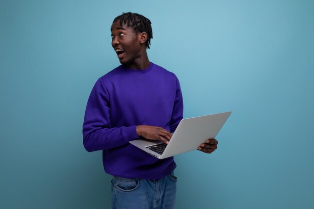 Verraste Amerikaanse jonge brunette man met dreadlocks met laptop