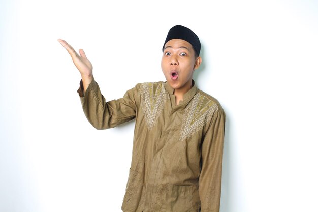 verraste aziatische moslim man die naar boven presenteert met open palm geïsoleerd op een witte achtergrond