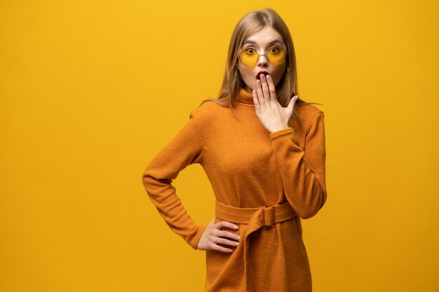 Foto verraste jonge vrouw die over gele muur schreeuwt