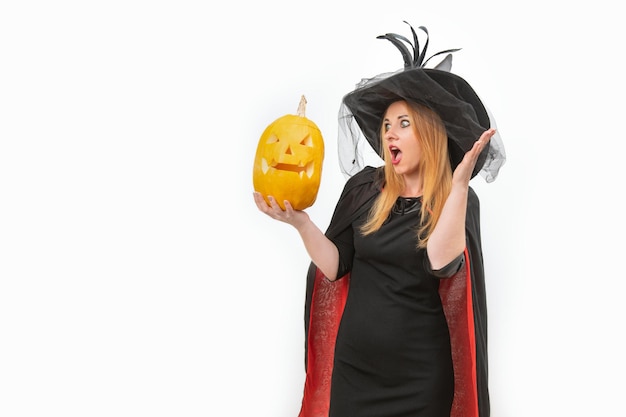 Foto verraste jonge vrouw in heksenhoed met jackolantern in haar handen halloweenfeest witte achtergrondruimte voor tekst