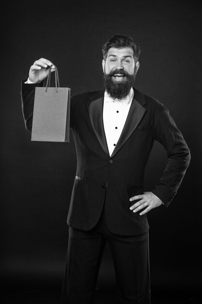 Foto verraste man in smoking vlinderdas formalwear op zwarte achtergrond met aankoop boodschappentas kopieerruimte