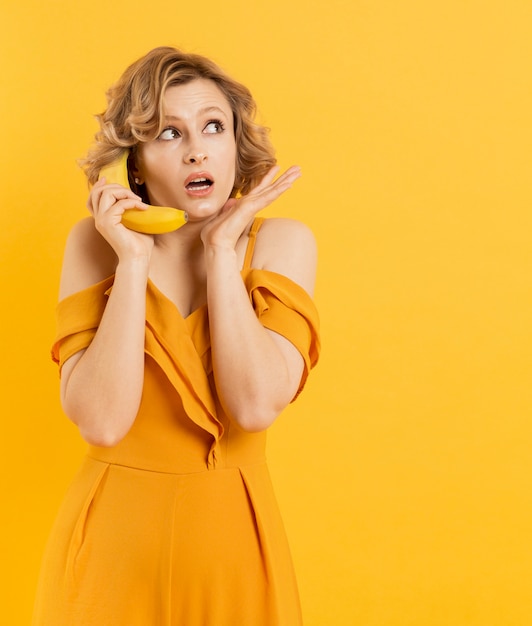 Verraste vrouw die banaan gebruikt als mobiel