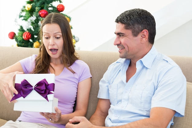 Foto verraste vrouw die het heden van kerstmis opent