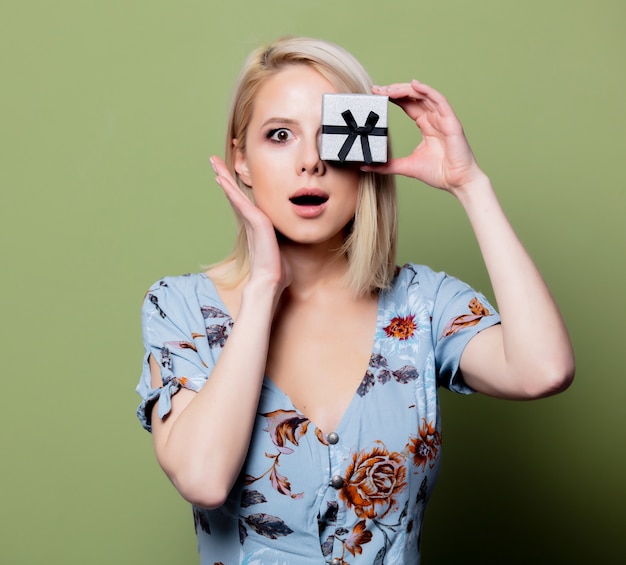 Verraste vrouw met giftdoos op groene muur