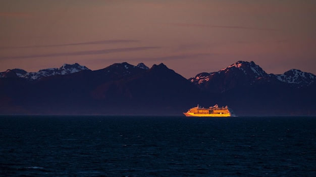 Foto verre cruiseschip verlicht door de ondergaande zon voor de kust van alaska