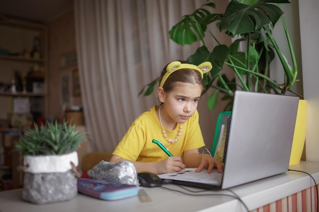 Verre onderwijs schattig schoolkind dat huiswerk bestudeert tijdens online les op sociale afstand thuis