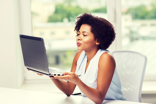 verre relatie, online communicatie en liefdesconcept - gelukkige jonge afro-amerikaanse vrouw die kus naar laptop stuurt