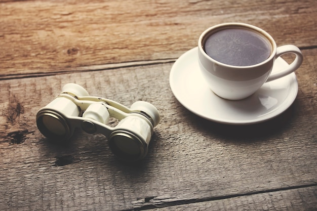 Verrekijker en koffie op de houten tafel