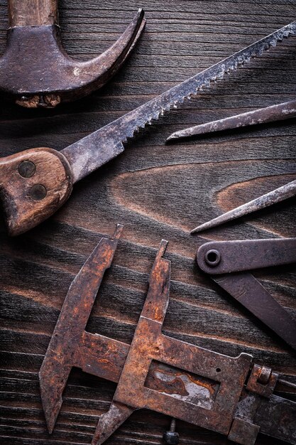 Verroeste vintage meetklauwen handzaag en klauwhamer op vintage houten plank bouwconcept