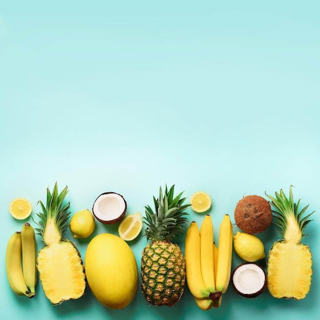 Vers biologisch geel fruit op blauwe achtergrond Vierkant gewas Monochroom concept met banaan kokos ananas citroen meloen Bovenaanzicht Kopie ruimte Popart design creatief zomer design