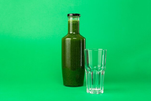 Vers bleekselderij-spinaziesap in een glazen fles en een leeg glas in de buurt van Gezond eten Detox-sapdieet