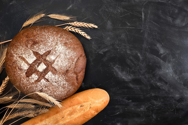 Vers brood en stokbroodtarwe op een donkere tafel Bovenaanzicht met kopieerruimte Bakkerijconcept