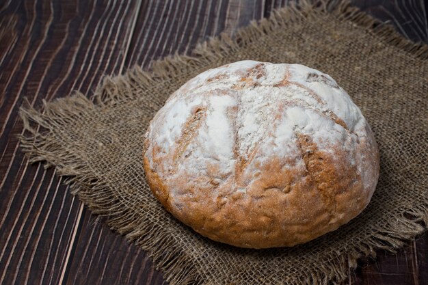 Vers brood met bloem erover op een doek boven een donkere houten tafel