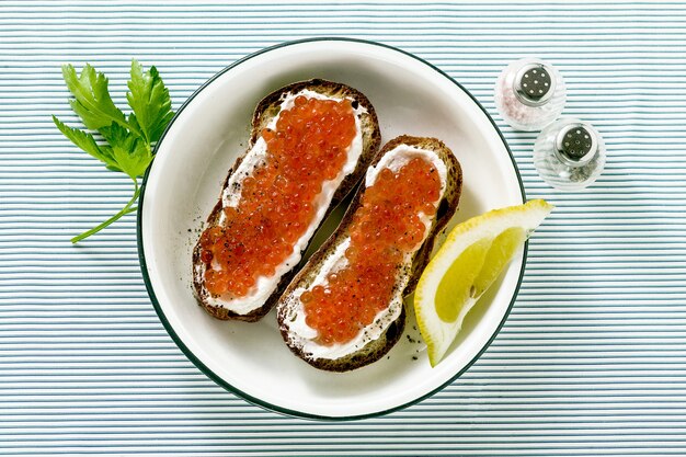 Vers brood sandwich met rode kaviaar en zachte kaas op een plaat. klassieke combinatie van ingrediënten.