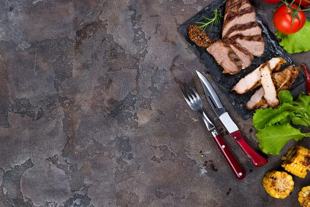 Vers drie soorten gegrilde biefstuk (varkensvlees, rundvlees) op leisteen bord met kruiden