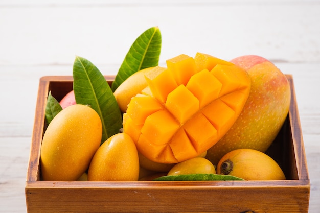 Vers en mooi mangofruit in een houten doos met in blokjes gesneden mangoblokjes op een lichte houten achtergrond, kopie ruimte (tekstruimte), blanco voor tekst