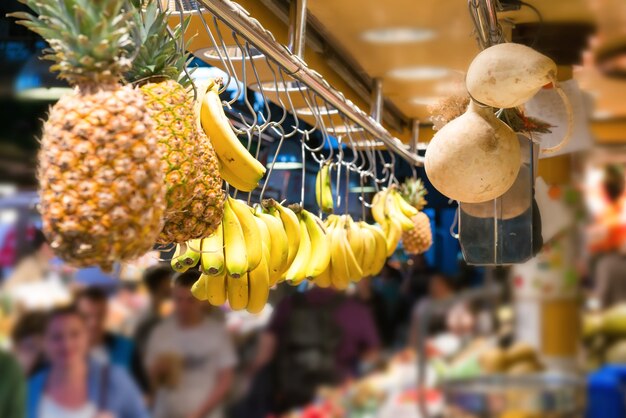 Vers fruit, bananen en ananas hangen op de voedselmarkt met massa's mensen