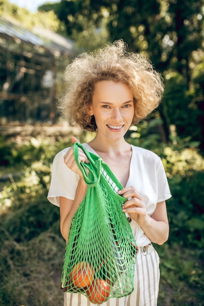 Vers fruit. jong meisje met een groene netzak met fruit in handen