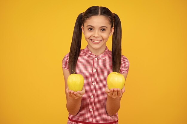 Vers fruit Tienermeisje houdt appels op gele geïsoleerde studioachtergrond Kindervoeding Gelukkige tiener positieve en lachende emoties van tienermeisje