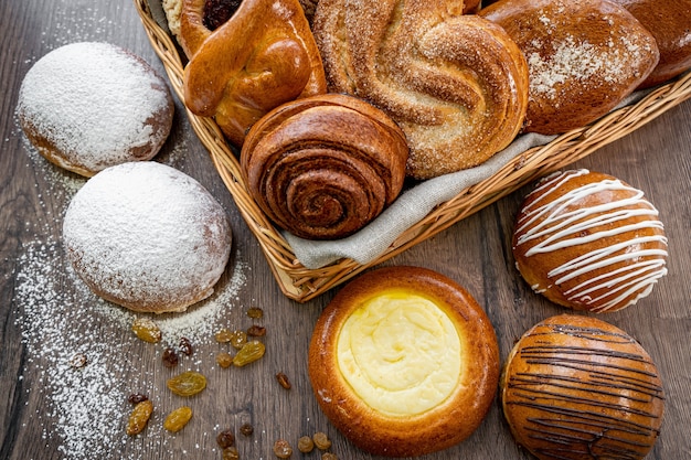 Vers gebak broodjes in de mand in rustieke stijl bakkerij met witte tarwe op houten tafel