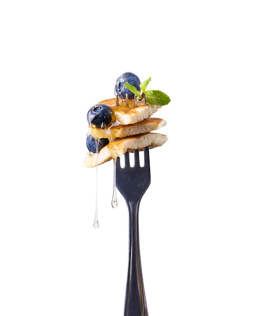 Vers gebakken Amerikaanse mini pannenkoeken op een vork met verse bessen lekker ontbijt witte achtergrond.