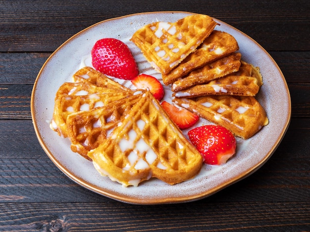 Vers gebakken Belgische Weense wafels bestrooid met poedersuiker met aardbeien