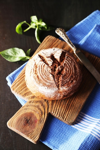 Vers gebakken brood en verse basilicum op snijplank op houten achtergrond