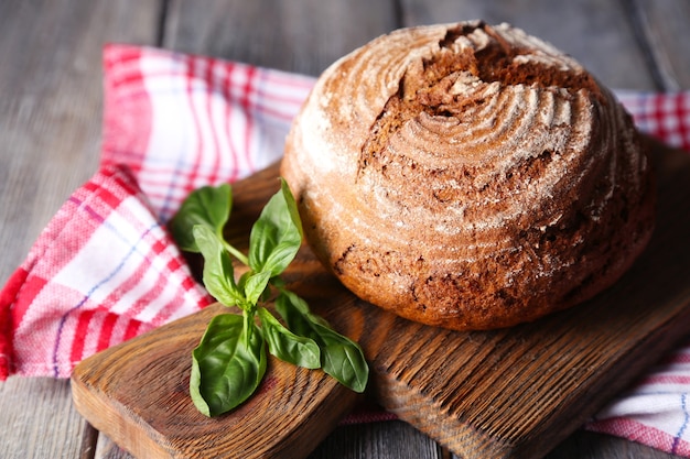 Vers gebakken brood en verse basilicum op snijplank, op houten tafel