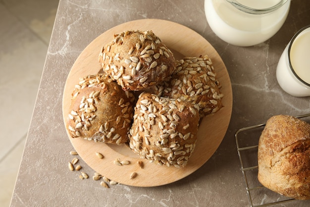 Vers gebakken broodjes en melk op grijze tafel