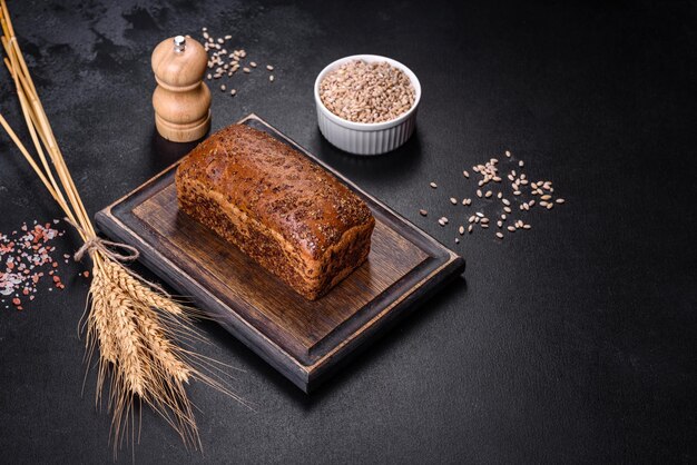 Vers gebakken bruin brood met oren en tarwekorrels op een donkere betonnen ondergrond