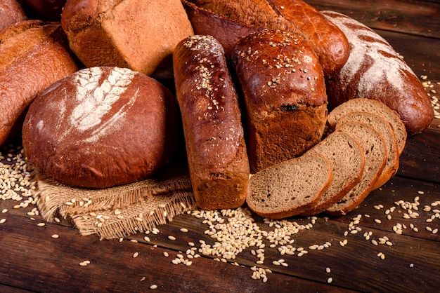 Vers gebakken bruin brood op een bruine houten achtergrond. Vers gebakken traditionele brood op een donkere achtergrond.