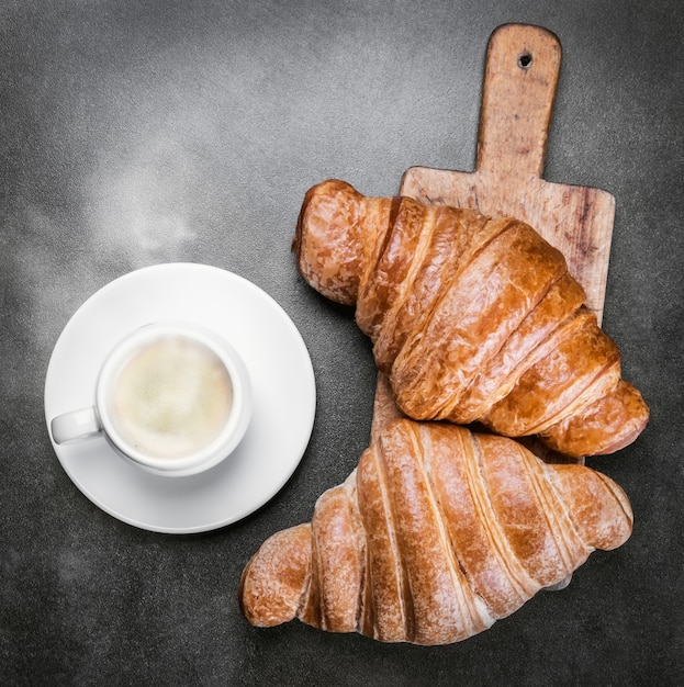 Vers gebakken croissants en een kopje koffie op tafel. het uitzicht vanaf de top