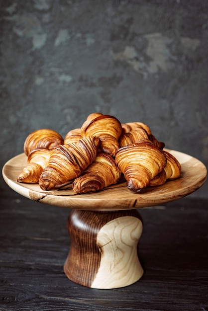 Vers gebakken croissants. Warme geurige botercroissants en broodjes op een houten standaard