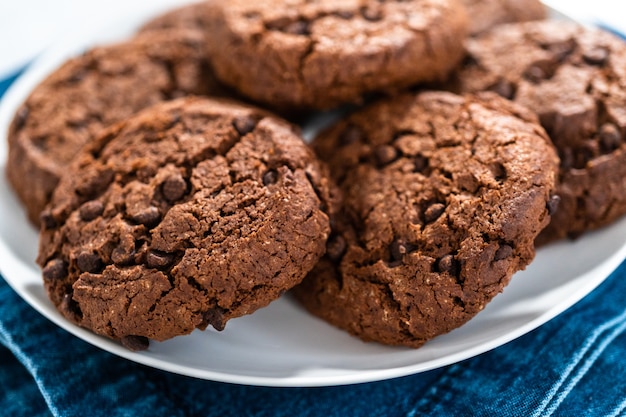 Vers gebakken dubbele chocoladeschilferkoekjes op een witte plaat.