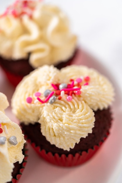 Vers gebakken fluwelen cupcakes met witte chocolade ganache frosting gedecoreerd met hagelslag