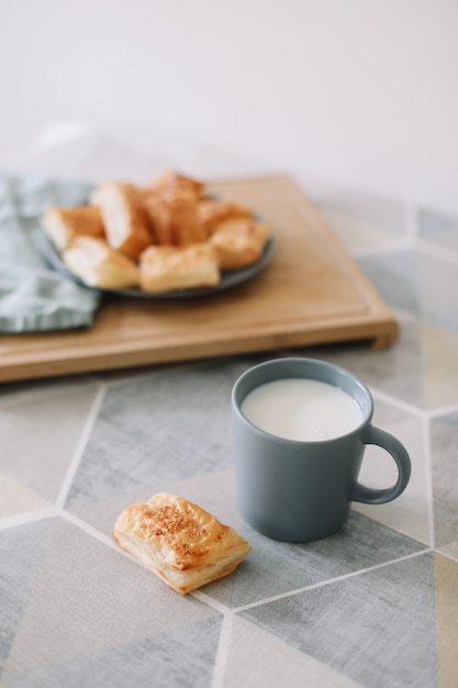 Vers gebakken huisgemaakt gebak op keukentafelontbijt met bladerdeegbroodjes en een glas melk