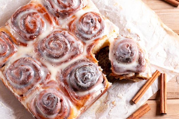 Vers gebakken kaneelbroodjes van kaneel met melksuikerglazuur op bakpapier