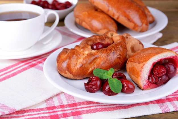 Vers gebakken pasteitjes met kers op plaat op tafel close-up