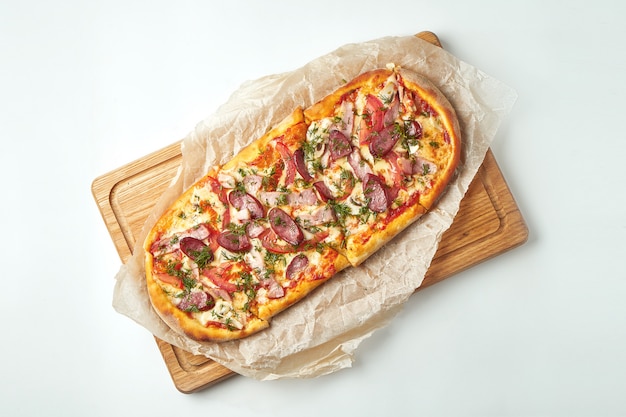 Vers gebakken pizza margherita met gerookte worst, spek, rode saus en mozzarella op een houten dienblad op een grijze tafel. Italiaanse keuken