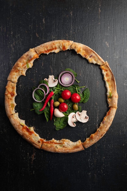 Vers gebakken pizza met ingrediënten op een donkere stenen tafel