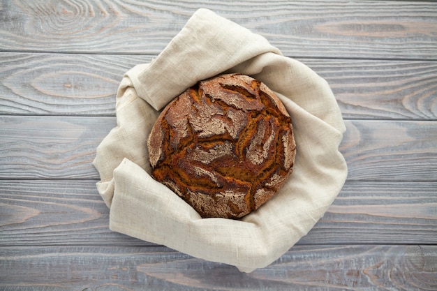 Vers gebakken roggebrood in een linnen doek op een houten achtergrond