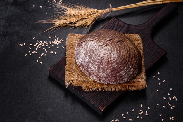 Vers gebakken zelfgemaakt bruin brood op een zwarte betonnen ondergrond met tarwekorrels