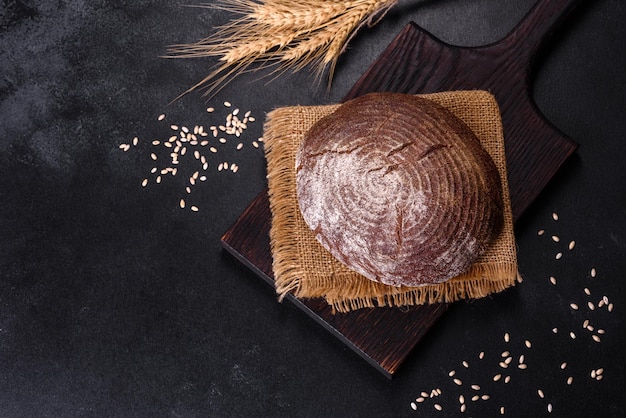 Vers gebakken zelfgemaakt bruin brood op een zwarte betonnen ondergrond met tarwekorrels