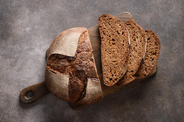 Vers gebakken zuurdesembrood met hennepmeel op snijplank ambachtelijk brood met zaden op grijze achtergrond
