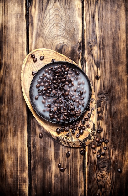 Vers gebrande koffie in de pan. Op houten achtergrond.